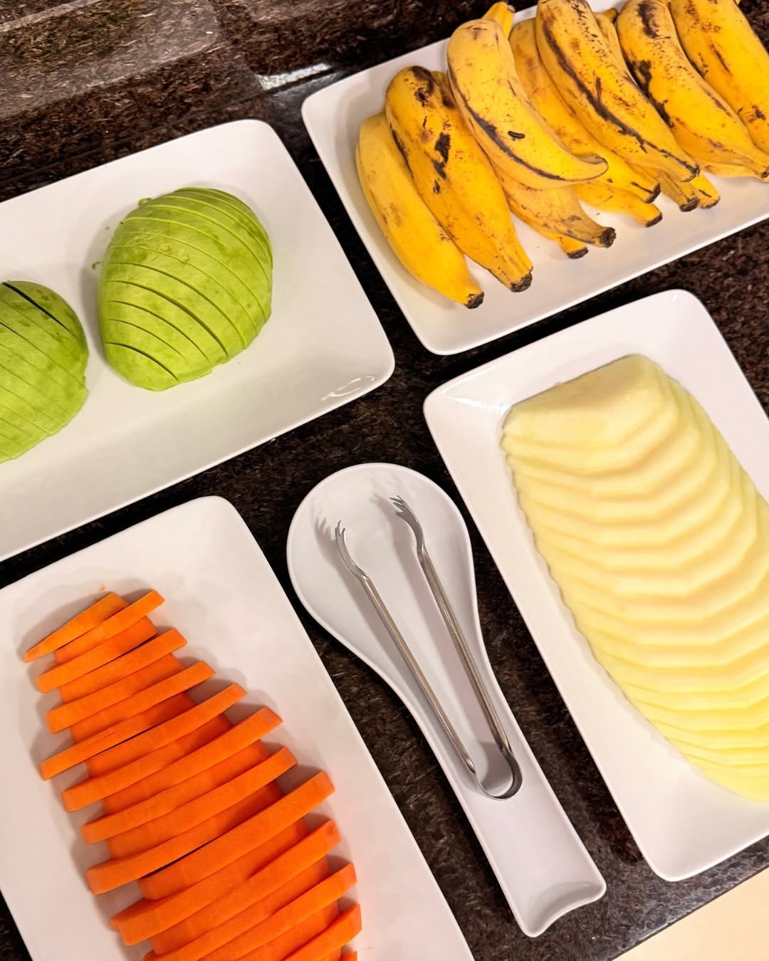 Travessas de frutas e legumes cortados: banana, melão, abacate e cenoura