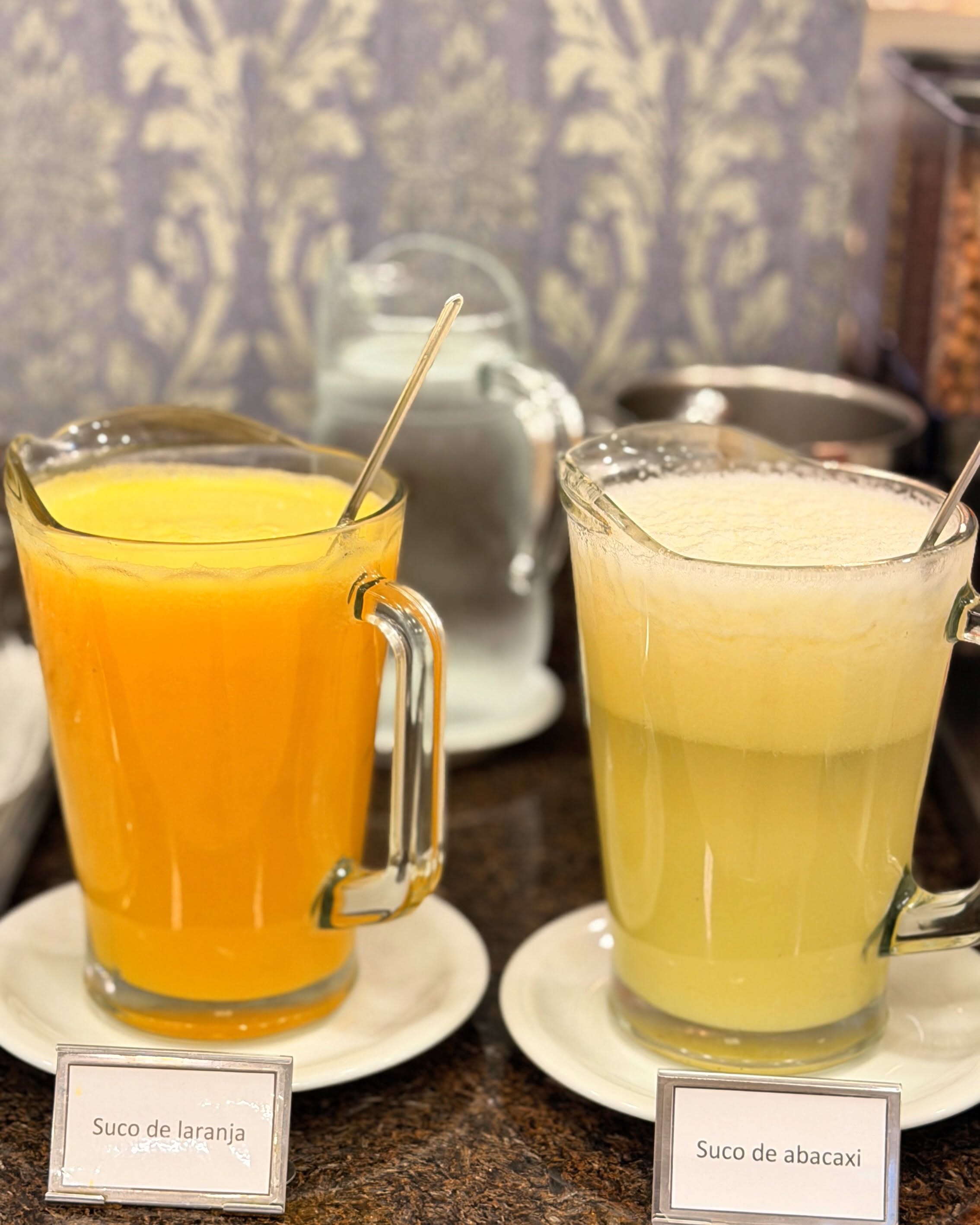 Jarras de suco de laranja e de abacaxi no bufê do café da manhã