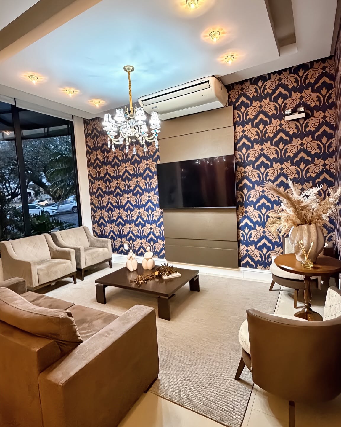 Sala de TV do hotel, com papel de parede damasco e poltronas